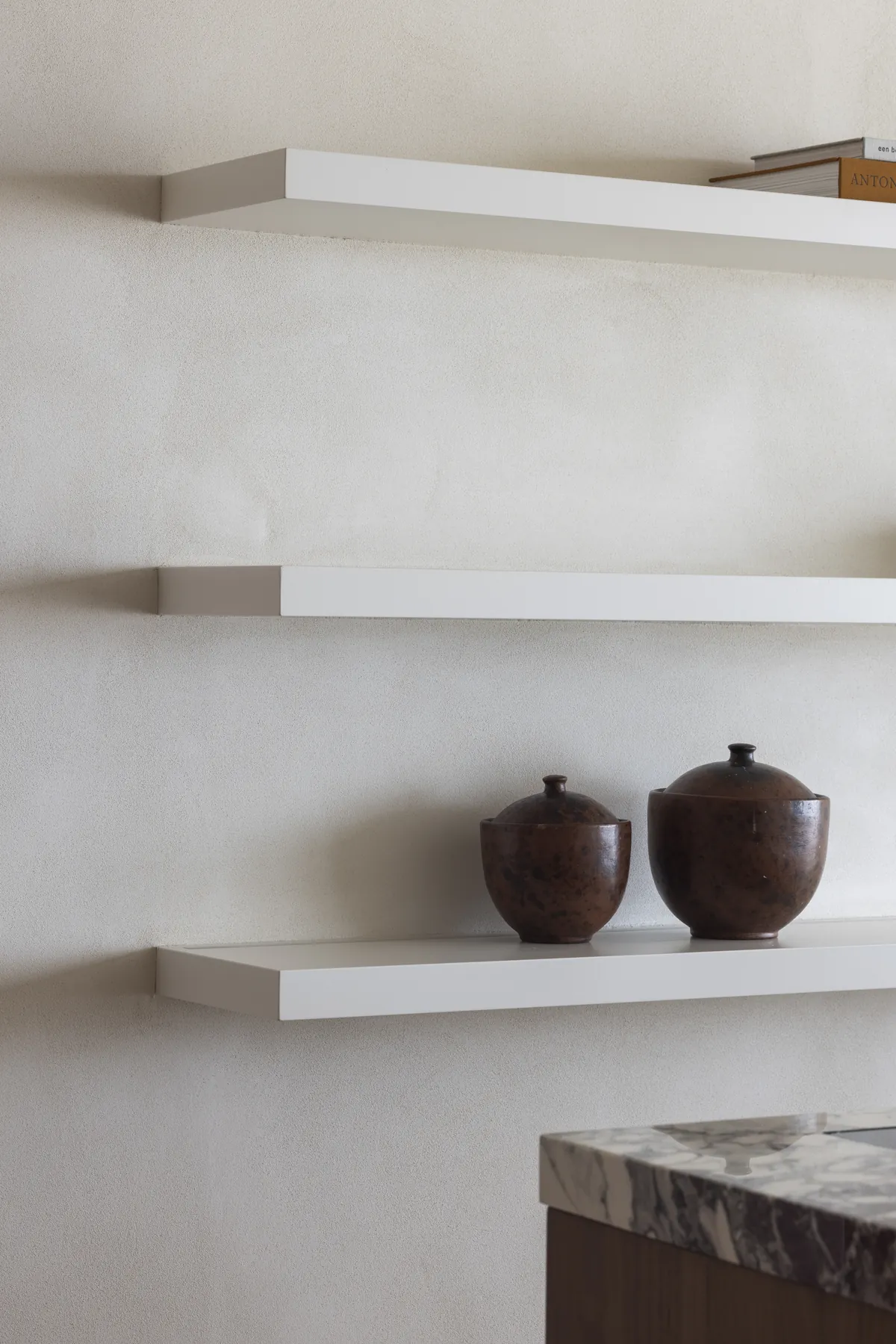 Minerale wandafwerking met zwevende legplanken