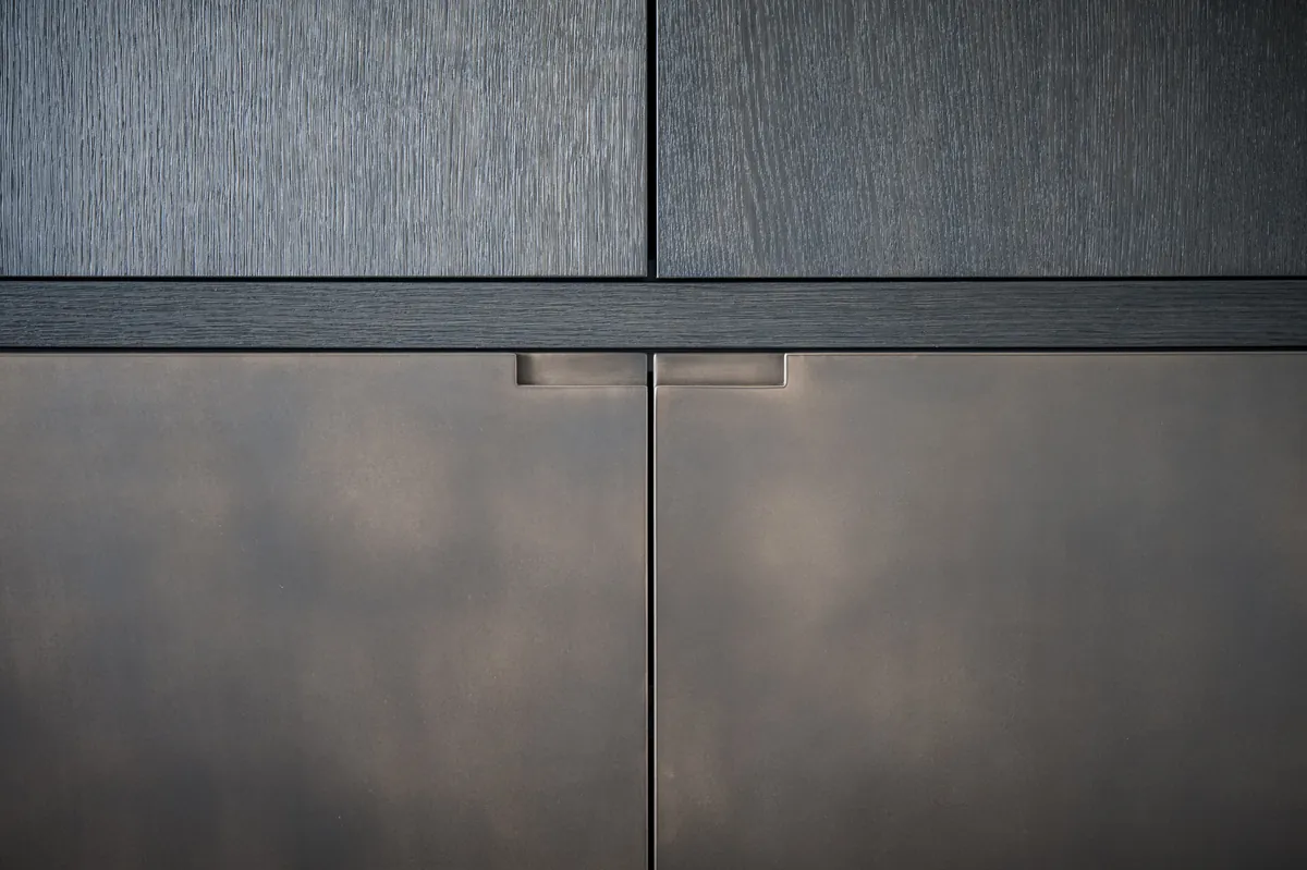 Detail van donker hout en gebronsde kastfronten